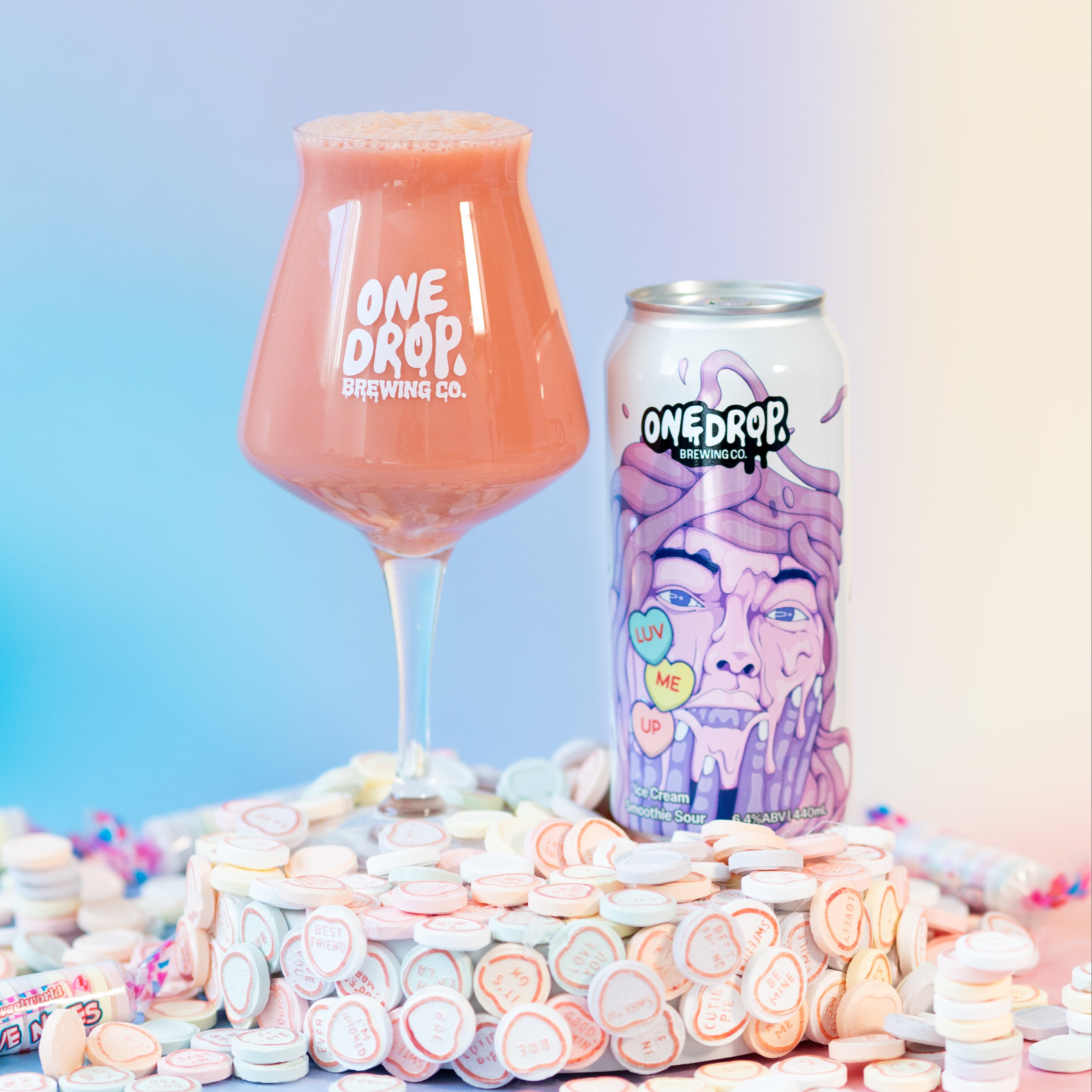 A glass of pink beverage and a can of One Drop Everything. Co.