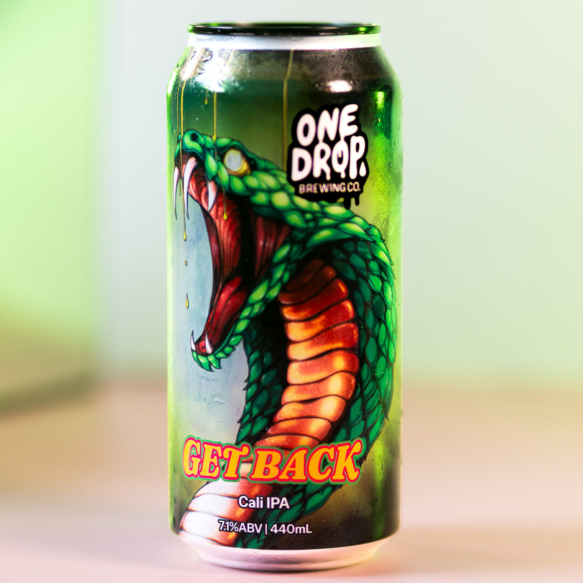 A 440mL aluminum can of One Drop Beer Brand's 'Get Back' Calm IPA, featuring a graphic illustration of a green and orange snake, set against a soft-focus green and pink background.