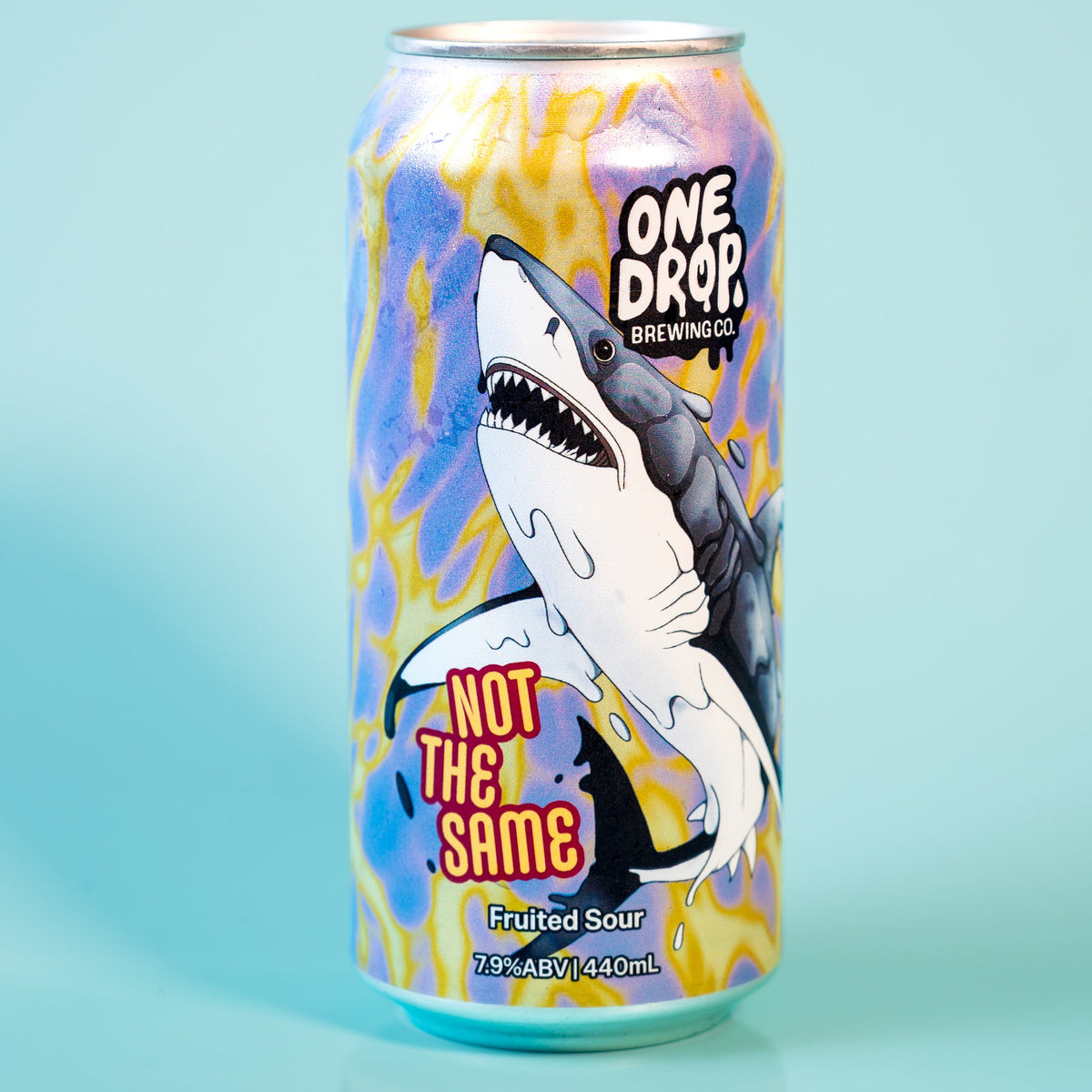 A single aluminum beverage can standing upright on a light blue surface against a pale blue background. The can features a shark illustration and the text 'ONE DROP' and 'NOT THE SAME'.