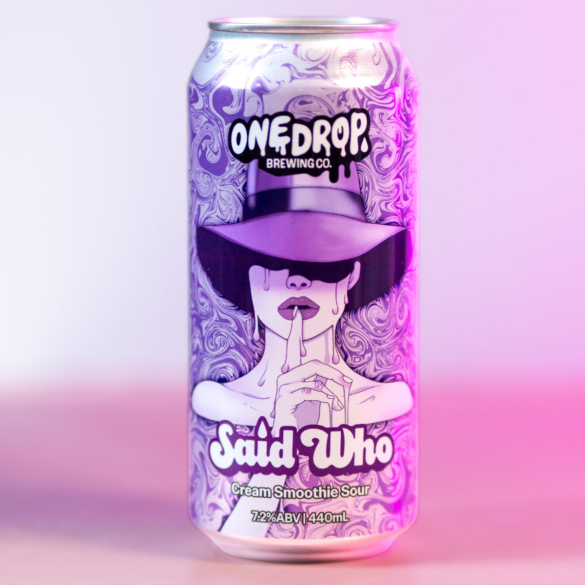 A single aluminum beverage can from One Drop Beverages, featuring a stylized illustration of a woman in a black hat and a purple-and-white patterned design, labeled 'Said Who'. The can is centered against a soft pink and purple gradient background.