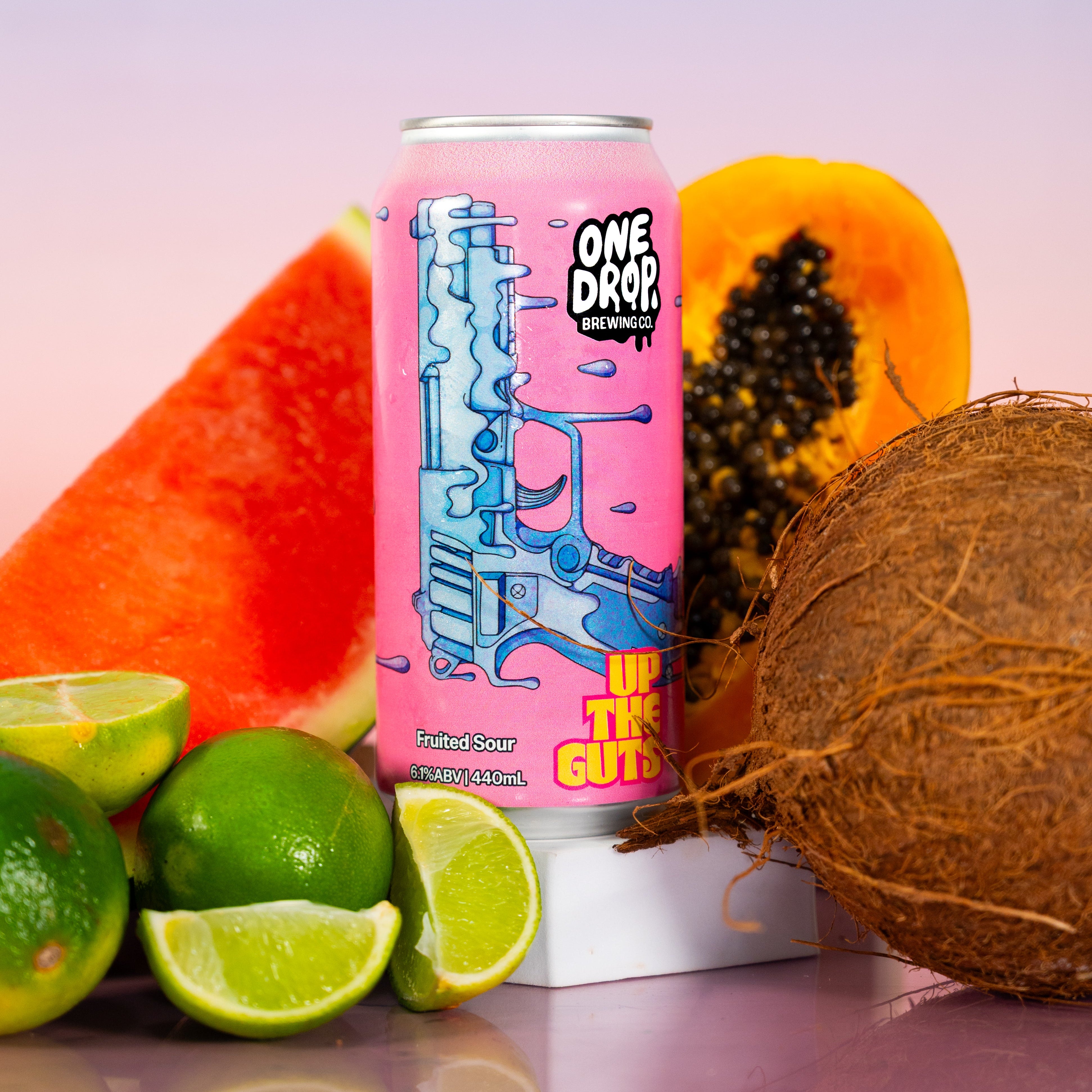 A can of One Drop Energy Drink on a white pedestal, surrounded by fresh fruit slices and a whole coconut against a pastel gradient background.